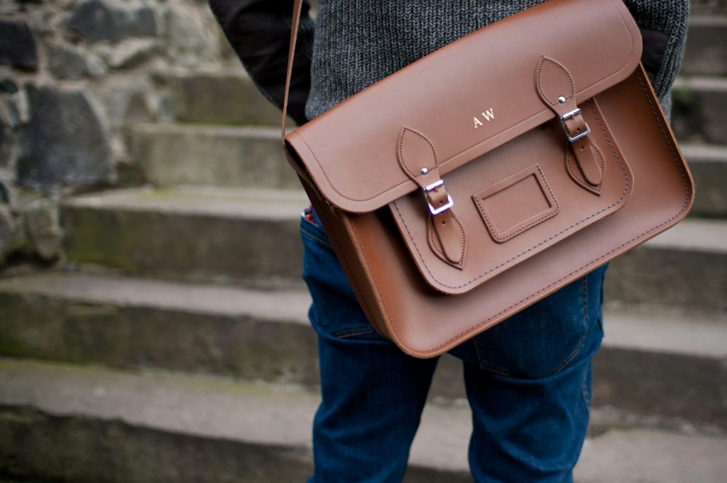 person carrying brown leather shoulder bag